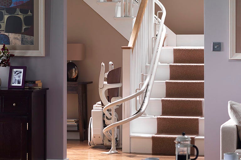 Stannah stairlift folded at the bottom of curved staircase