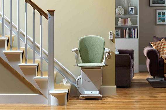 green stairlifts at bottom of stairs with brown sofa