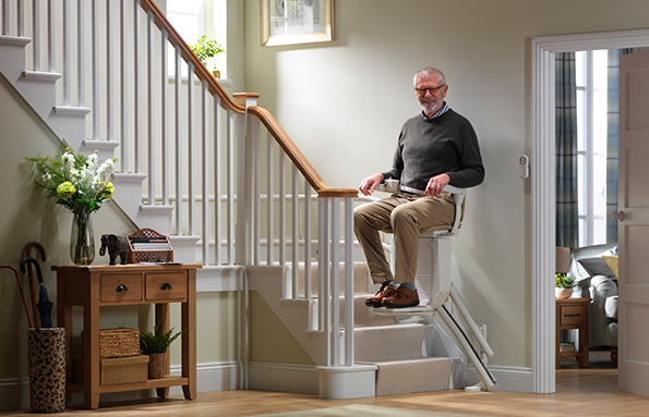man travelling on stairlift with dark green jumper