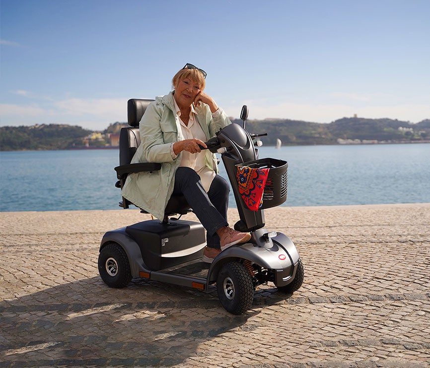 ana bola em scooter de mobilidade reduzida junto ao rio