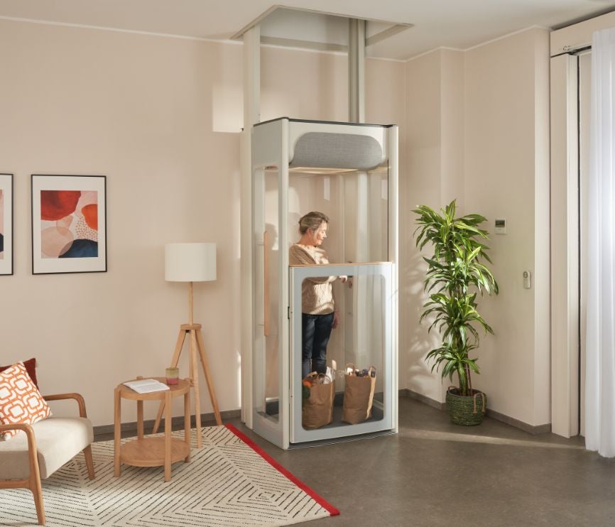 Una donna disabile è sul suo ascensore Uplifts S2 con la spesa e si dirige al 1° piano