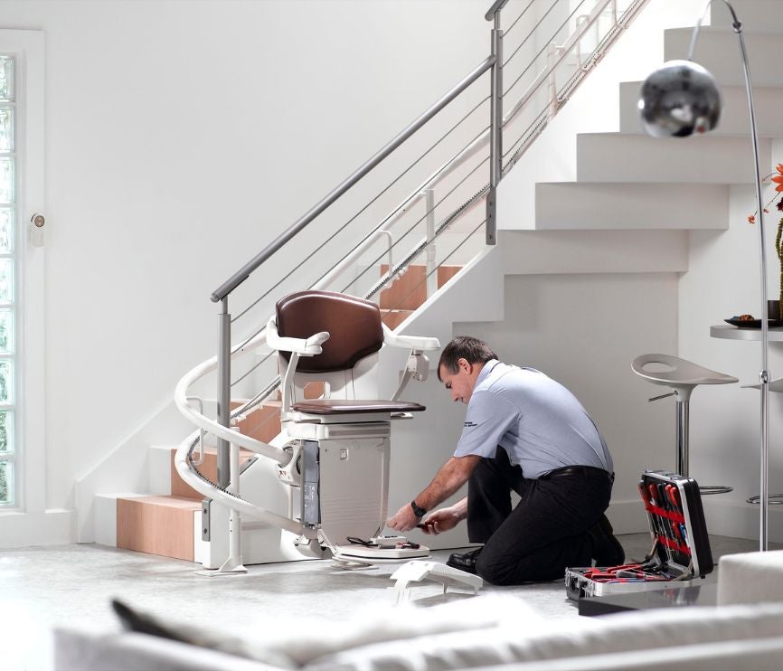 Technicus van Stannah verwijdert een gebogen traplift van een trap.