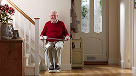 man with glasses sat on stairlift