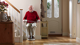 man sat with red jumper and glasses on stairlift