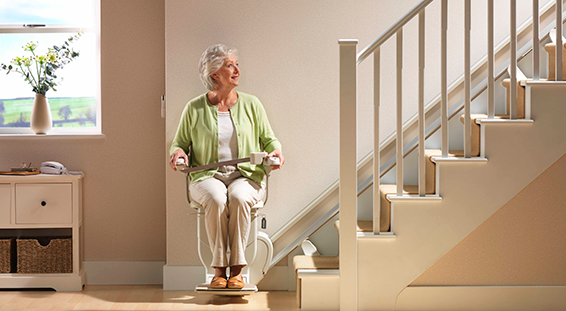 Lady sitting on stairlift with seatbelt on looking up the stairs