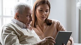 man and younger lady looking on ipad