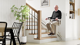 man on stairlift with white wall
